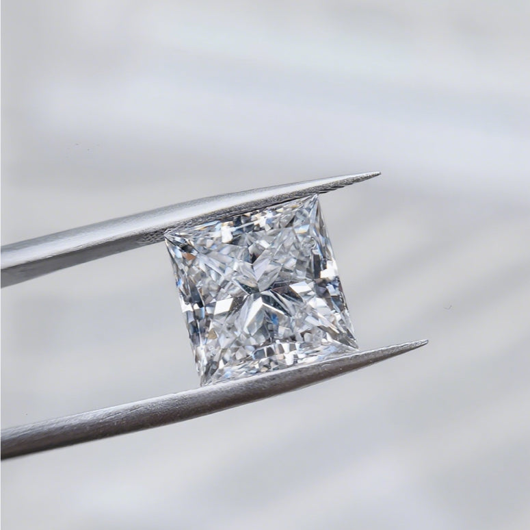 A square cut diamond is held in tweezers to show its clarity